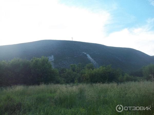 гора с пещерами и крестом